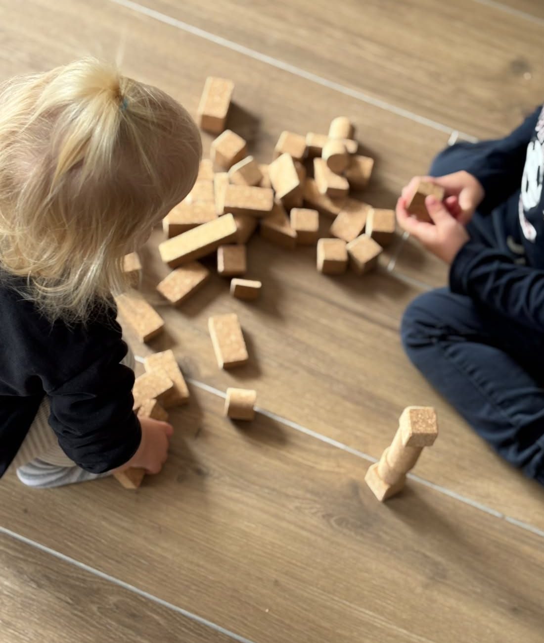 Zwei Kinder spielen gemeinsam mit nachhaltigen Korkbausteinen von korkino und bauen verschiedene Formen.